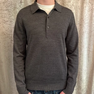 Mörkgrå stickad pikétröja från Uniqlo - Säljer en stilren mörkgrå stickad pikétröja från Uniqlo i herrstorlek XS. Tröjan har lång ärm, klassisk krage och knäppning framtill. Materialet är mjukt och tunt stickat, perfekt för lager-på-lager. Perfekt för sommarkvällar. Skick 9/10 och nypris 800 om jag inte minns fel!