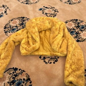 Gul pälsjacka croppad modell - Säljer en supermjuk och fluffig gul faux pälsjacka i croppad modell. Jackan har lång ärm och är helfodrad på insidan. Perfekt för dig som vill sticka ut med färg och stil.