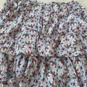 Blommig volangklänning från Zara - Supersöt blommig klänning från Zara i storlek S. Klänningen har volangdetaljer och ett ljust blått tyg med lila och vita blommor. Perfekt för vår och sommar! 💐