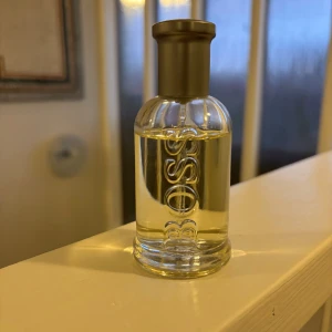 BOSS Bottled Eau de Toilette - Klassisk herrparfym från Hugo Boss i en genomskinlig glasflaska med silverfärgat lock. Doften är fräsch och maskulin, perfekt för dig som gillar eleganta och tidlösa parfymer. Flaskan har BOSS-loggan ingraverad på framsidan. Och är inte använd mer än 3 gånger