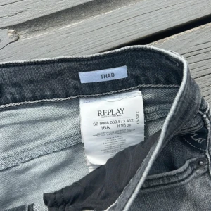 Grå jeansbyxor från Replay - Säljer ett par grå jeansbyxor från Replay med klassisk femficksdesign och raka ben. Jeansen har normal passform och stängs med dragkedja och knapp. Perfekta för dig som gillar en avslappnad stil.