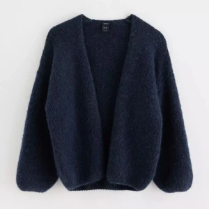 Mörkblå stickad kofta - Mysig och enkel mörkblå stickad kofta med lång ärm och öppen front. Koftan har en mjuk och fluffig känsla. Storlek M/L men den är mer en M aldrig använd