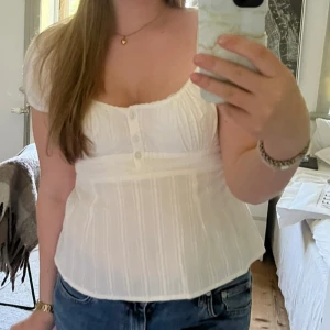 Babydoll Topp - Hej hej! Säljer en söt babydoll vit blus från Nelly med korta puffärmar och knapp detalj . Blusen har en smickrande passform med resår i ryggen. Hör av dig vid frågor/intresse! 💞