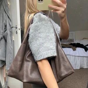Brun axelväska i skinn - Snygg och rymlig brun axelväska i skinn. Perfekt för att bära med sig allt man behöver under dagen. Väskan har en enkel och stilren design som passar till många olika outfits. Köpt second hand, nypris sunt 700!