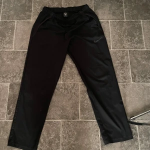 Svarta träningsbyxor från Nike - Säljer ett par svarta träningsbyxor från Nike med Dri-FIT teknologi. Perfekta för träning eller en avslappnad dag. Helt okej skick. 