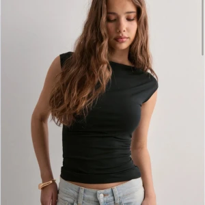 Svart ärmlös topp - Snygg svart ärmlös topp med en tight passform. Perfekt för en stilren look, oavsett tillfälle. Toppen har en enkel design som gör den lätt att matcha med olika outfits.