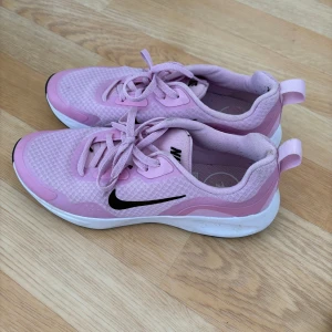 Rosa Nike sneakers - Säljer ett par snygga rosa Nike sneakers med svart swoosh. Skorna har snörning och en bekväm sula, perfekta för vardagsbruk eller träning. De har en sportig design med en ljusrosa nyans och vit sula.