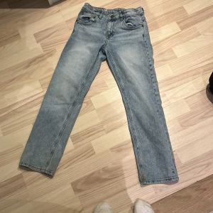 Ljusblå jeansbyxor - Säljer ett par ljusblå jeansbyxor med klassisk femficksdesign. Byxorna har en rak passform och är tillverkade i ett slitstarkt denimtyg. Perfekta för en avslappnad stil.