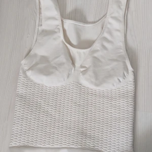 Vit ribbad linnetopp från C2Salus - Säljer en vit compression linnetopp från C2Salus med en unik ribbad textur på nedre delen. Tillverkad i Italien. Den är väldigt stretchig så passar även xxs, xs och om man vill ha den riktigt tajt s