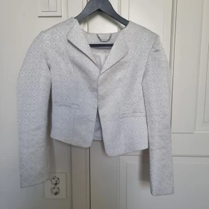 Vit kavaj från Stockh LM - vit kavaj från Stockh LM med ett geometriskt mönster. Kavajen har en kort och är i storlek 36. Finns en gul fläck på insidan men syns inte så mycket. På ärmarna finns dragkedjor (se sista bilden) 