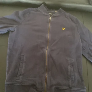 Mörkblå Half Zip-Up Tröja - Säljer en snygg mörkblå Half Zip-Up Tröja  med dragkedja och det klassiska gula logotypen på bröstet. Perfekt för en avslappnad stil. Den har långa ärmar och praktiska fickor framtill. Använd endast ett par gånger och är köpt för 1099 Kr. Storleken är Xl, och priset går givetvis att diskuteras💯