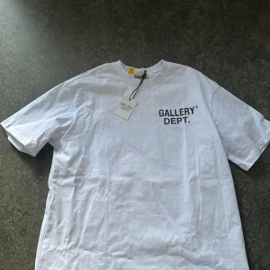 Vit t-shirt från Gallery Dept. - Säljer en stilren vit t-shirt från Gallery Dept. Aldrig använd men säljer den för att den är lite för stor på mig, står att det är S men passar hundra procent M. Tryck på båda sidorna med taggen kvar. Priset kan diskuteras!