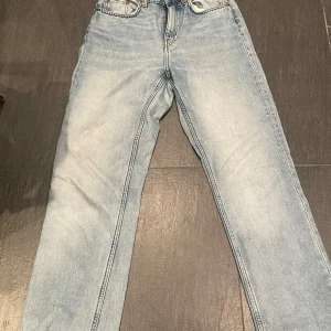 Ljusblå jeansbyxor - Snygga ljusblå jeansbyxor med en klassisk femficksdesign. De har en rak passform och är perfekta för en avslappnad stil. Byxorna har en knapp och dragkedja framtill. Byxorna är ifrån weekday.