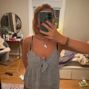 Blommig linnetopp från NA-KD - Säljer en söt blommig linnetopp från NA-KD. Toppen har smala axelband och en knytning framtill. Perfekt för varma dagar med sitt lätta och luftiga material.