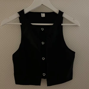 Urringad topp - En svart urringad/öppen topp fram från H&M i storlek S. Den är smyckad med silvriga hjärtan fram. Stretchigt material. Testad men aldrig använd. 