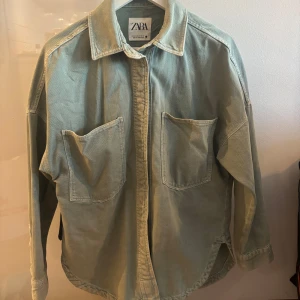 Grön jeansjacka från Zara - Säljer en stilren grön jeansjacka från Zara. Jackan har två stora bröstfickor och en klassisk krage. Jackan är xxs men sitter som en storlek M. 