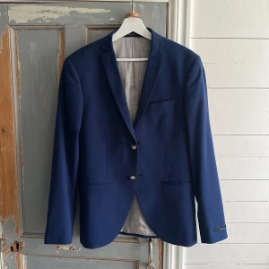 Kavaj paket  - Snygg blå kavaj med två knappar och en vit slim fit skjorta från Stockholm Kravatt. Kavajen har en klassisk design med fickor och en stilren look. Skjortan är i bomull med svarta detaljer på kragen.  Kavajen- storlek 46 skjortan- storlek s och byxorna storlek 44. Hör av er vid mer funderingar 