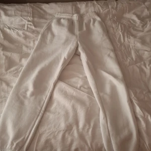 Vita mjukisbyxor från Gina Tricot - Säljer ett par vita mjukisbyxor från Gina Tricot. De har en elastisk midja och är gjorda i ett mjukt material som är perfekt för en avslappnad stil. Är i helt nytt skick