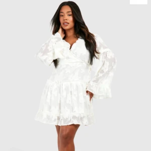 Vit klänning med volang - Säljer min jättefina krämvita klänning från Boohoo! Använd en gång, säljer då jag inte använder den längre. Inga tecken på användning. Hör av er för fler bilder eller om ni har några frågor.