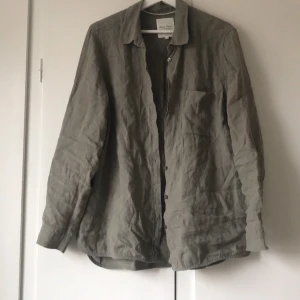 Grå linneskjorta - Snygg grå skjorta i linne från Part two. Skjortan har en klassisk krage och knappar framtill. Perfekt för en stilren look. Strl M