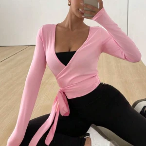 Rosa omlottopp 💗 - Säljer en söt rosa omlottopp med långa ärmar och knytband i midjan. Perfekt för en stilren och bekväm look. Toppen har en v-ringad design som ger en elegant touch.