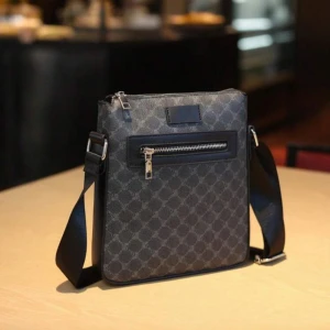 Mörkgrå axelväska med mönster - Snygg mörkgrå axelväska med diskret rutigt mönster och justerbar axelrem. Väskan har en dragkedja upptill och en praktisk ytterficka med dragkedja framtill. Perfekt för att bära med sig det viktigaste.