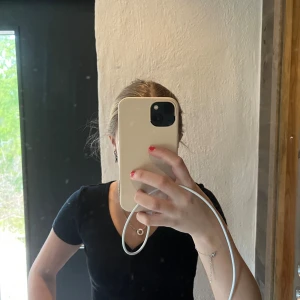  topp från Pull&Bear - Säljer en svart croppad topp från Pull&Bear med ribbad struktur och v-ringning. Toppen har korta ärmar och knappar framtill, perfekt för en trendig och enkel look.