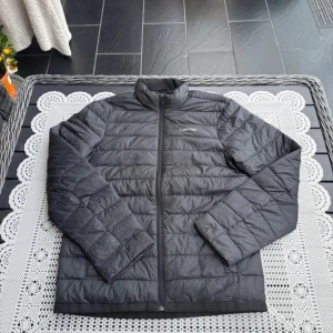 Svart quiltad jacka från Carinthia - Säljer en stilren svart quiltad jacka från Carinthia. Jackan har en dragkedja framtill och är perfekt för kyligare dagar. Den har en klassisk design med långärmade ärmar och en bekväm passform.