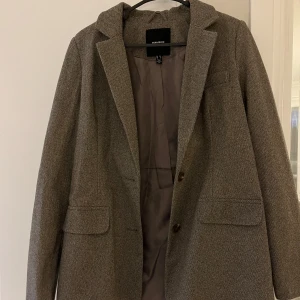 Brun oversize kavaj från Vero Moda - Snygg brun kavaj från Vero Moda med klassisk design i lite grövre tyg. Fungerar såväl inne som ute. Kavajen har två knappar framtill och fickor med lock. Endast använd ett par gånger.