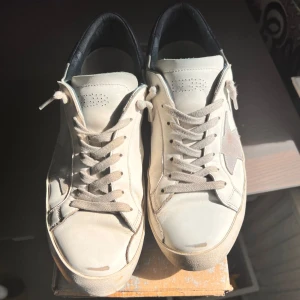 Vita golden goose - Snygga vita sneakers från Golden Goose med en ikonisk stjärndetalj i silver på sidan. Skorna har en rund tå och snörning framtill. Hör av dig vid minsta fundering!
