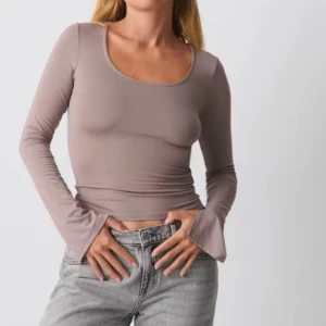 Beige långärmad croppad topp från Gina Tricot - Säljer en beige långärmad topp från Gina Tricot. Modellen är croppad med utsvängda ärmslut och har en rundad, djup urringning. Perfekt att styla med jeans eller kjol för en trendig look.