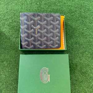 Blå lyxig plånbok  - Säljer en elegant plånbok  med deras ikoniska mönster i blått och vitt. Plånboken har flera kortfack och en stilren design som passar perfekt för den modeintresserade.