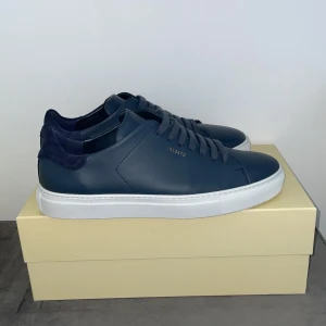 Axel Arigato Clean 90 – storlek 42 – Nyskick - Säljer ett par stilrena Axel Arigato Clean 90 sneakers i storlek 42. Skorna är i nästan helt nyskick, endast använda en gång. 	•	Färg: Mörkblå med vit sula 	•	Material: Premiumläder 	•	Nypris: ca 2 200 kr 	•	Levereras i originalkartong  Passar perfekt både till vardag och mer uppklädda tillfällen. Säljes då de inte riktigt passade i storleken. Pris kan diskuteras!