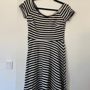 Svartvit randig kortklänning - Snygg kortklänning med svartvita ränder och rundad halsringning. Bredare upptill så ärmarna kan hamna på överarmarna om man vill.