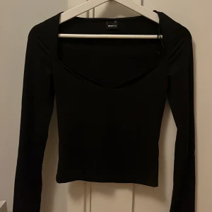 Svart långärmad topp Gina Tricot XS - Säljer en svart långärmad topp från Gina Tricot i storlek XS. Toppen har en snygg v-ringning och figurnära passform, perfekt att styla med jeans eller kjol. Enkel och stilren design som funkar till många looks.