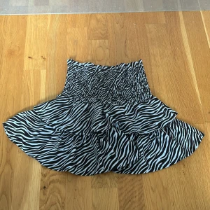 Zebramönstrad axelbandslös topp från Gina Tricot - Superfin axelbandslös topp från Gina Tricot med svartvitt zebramönster. Toppen har dubbla volanger och  storleken är 134/140. Toppen är i nyskick och mitt pris är 99kr.
