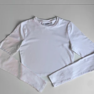 Vit långärmad tröja från Weekday - Långärmad tröja från Weekday. Modellen är croppad med rund halsringning och raka ärmar. 