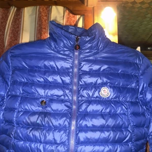  Moncler jacka  - Säljer denna riktigt feta Moncler jacka med den  klassiska loggan på bröstet. Västen har quiltad design, dragkedja framtill och praktiska fickor med dragkedja. Perfekt som skidjacka men även toppen till att ha i vardagen. Storlek 5 i Moncler vilket motsvarar L eller XL. Vid ytterligare frågor och funderingar är det bara att skriva i annonsen.                 Mvh Moses