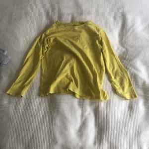 Gul långärmad tröja från Lindex - En basic gul långärmad tröja från Lindex i 100% bomull. Enkel och skön modell med rund halsringning, perfekt att matcha med jeans eller shorts. Passar dig som gillar färg och vill ha en mjuk tröja till vardags.