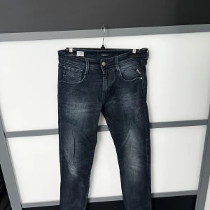 Replay mörkblå jeans slim fit - Snygga mörkblå jeans från Replay med diskreta slitningar och klassisk femficksdesign. Jeansen har slim passform och raka ben, med detaljerade sömmar och logotyp på fickan.
