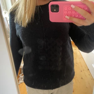 mörkblå stickad tröja från Yessica - Mysig mörkblå stickad tröja från Yessica med rund halsringning och diskret söm framtill. Tröjan har lång ärm och en klassisk, enkel design som är lätt att matcha.