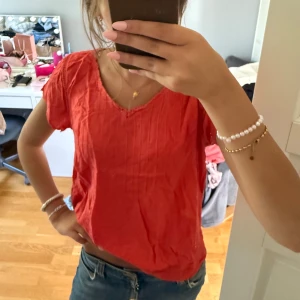 Röd blus med v-ringning - Säljer en typ korall färgad blus med v-ringning och korta ärmar. 