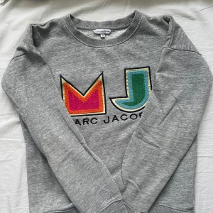 Grå sweatshirt  - Grå sweatshirt från Marc Jacobs med märke framtill.  Super snygg, har använts mycket och är därför lite slitet längst ut på armarna (bild 3 och 4). Det är barnstorlek 150, är som Xs 