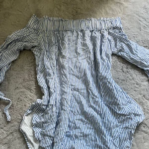 Randig offshoulder blus H&M - Snygg blåvit randig blus från H&M med offshoulder och långa ärmar. Blusen har en avslappnad passform och är perfekt för varma dagar. 