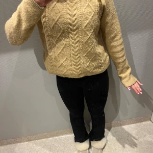 Beige stickad tröja - Säljer en mysig beige stickad tröja med ett snyggt kabelstickat mönster. Tröjan har långa ärmar och en normal passform, perfekt för kyliga dagar. Passar bra till både jeans och kjol.