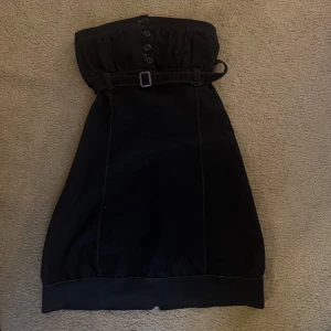 Mörkblå axelbandslös klänning med bälte - Snygg mörkblå axelbandslös klänning med knappar och bälte i midjan. Perfekt för en stilren look. Klänningen har en smickrande passform och är enkel att matcha med olika accessoarer.