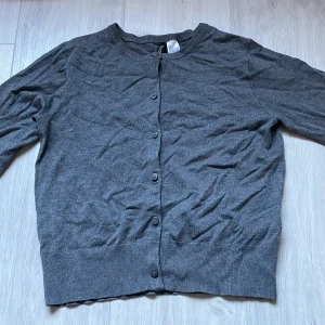 Grå kofta från H&M - Säljer en stilren grå kofta från H&M. Den har långa ärmar och knappar framtill. Perfekt för lager-på-lager och passar till många olika outfits. Ett måste i garderoben!🍸💋
