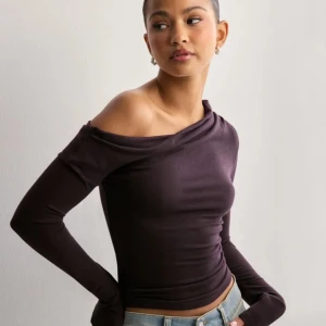 Nelly tröja - Snygg svart offshoulder topp med lång ärm. Jätte skönt material. Som ny! Inga defekter kanske använt 1 gång. Storlek Xs . Den är typ vinröd blandat med lila! 