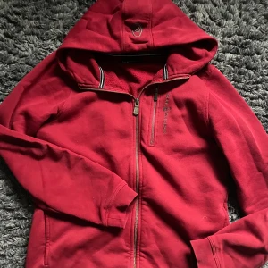 Röd zip hoddie - Sail racing 🏎️  - Säljer en snygg röd zip hoddie från Sail Racing med dragkedja och huva. Den är i ett mycket fint skick och har inga skador eller fel. Storlek 176 (xs). 