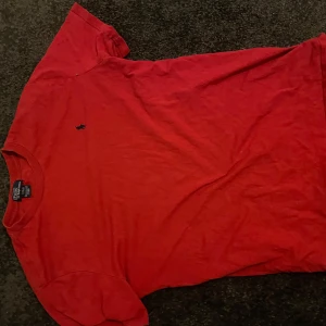 Röd t-shirt från Polo Ralph Lauren - Säljer en klassisk röd t-shirt från Polo Ralph Lauren med det ikoniska broderade logotypen på bröstet. T-shirten är kortärmad och tillverkad i mjuk bomull. Perfekt för en avslappnad stil.
